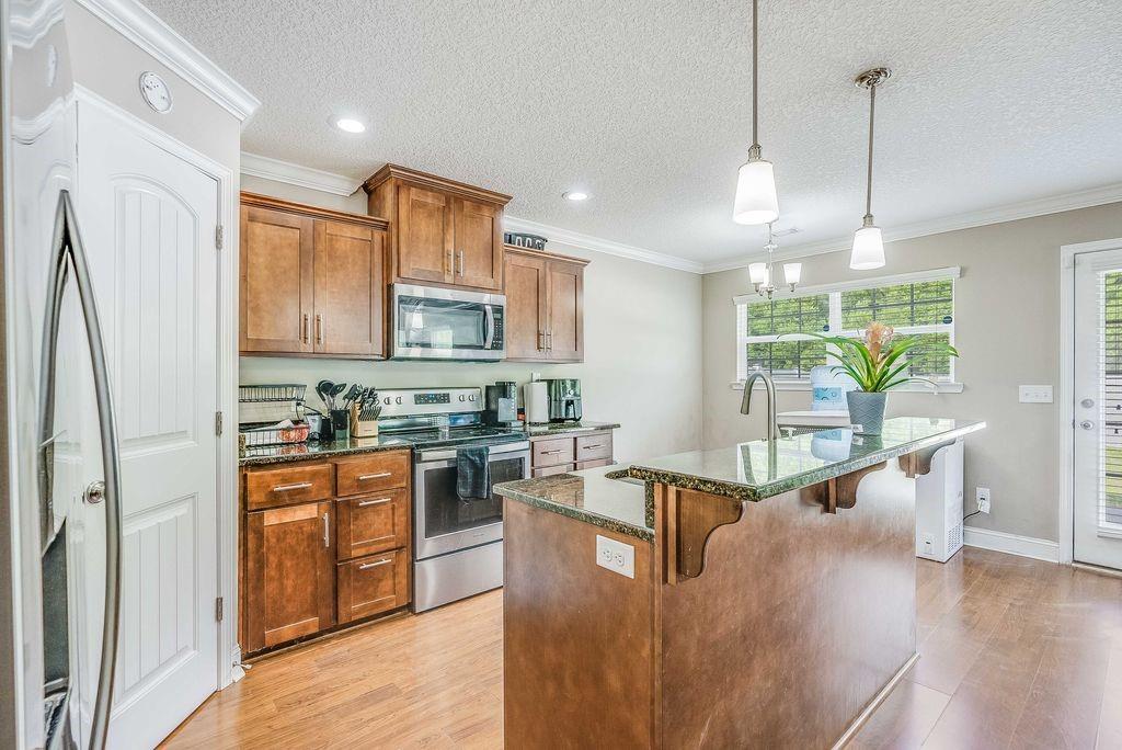 1200 Cypress Fall Circle Hinesville, GA 31313 - Photo 6 of 24 a kitchen with stainless steel appliances granite countertop a refrigerator a sink dishwasher a stove and white countertops with wooden floor