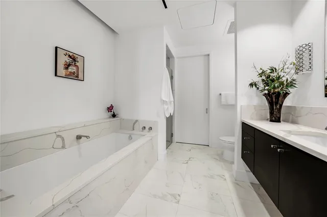 a spacious bathroom with a tub sink and mirror