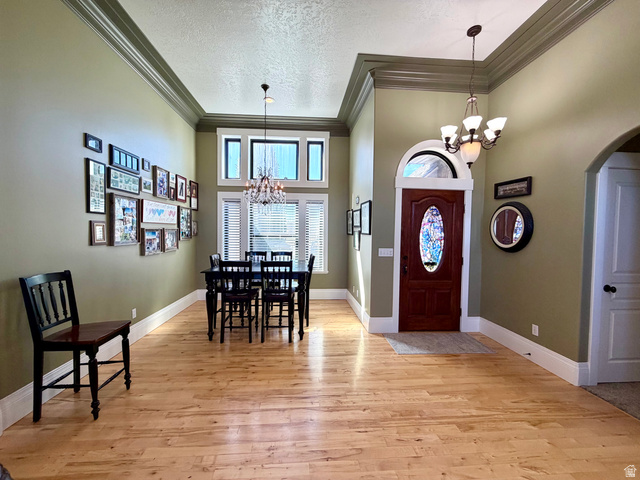 202 375 West Providence, UT 84332 - Photo 7 of 61 Dining space featuring a chandelier, a high textured ceiling, light wood-style flooring, arched walkways, and ornamental molding