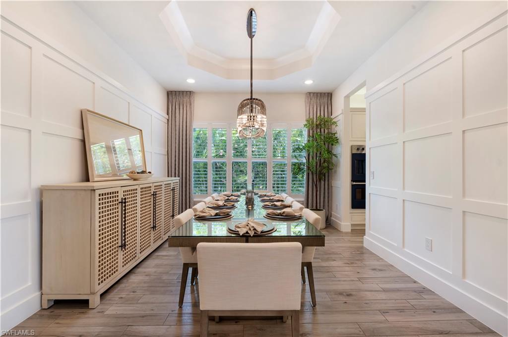 4353 Caldera Circle Naples, FL 34119 - Photo 13 of 40 a dining room with wooden floor a chandelier a wooden table and chairs