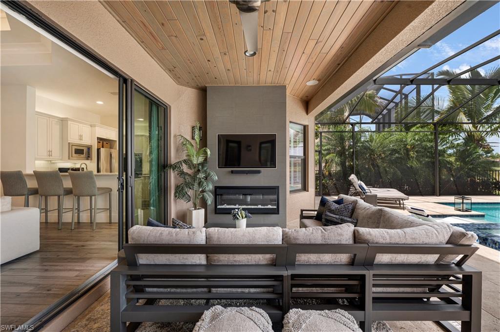 4353 Caldera Circle Naples, FL 34119 - Photo 24 of 40 a living room with furniture a flat screen tv and a floor to ceiling window