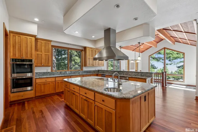 a kitchen with stainless steel appliances granite countertop a sink a stove and a wooden floors
