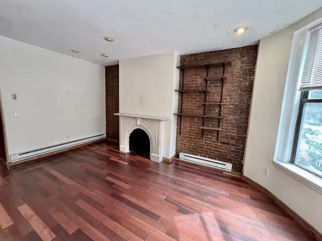 a view of empty room with wooden floor and fireplace