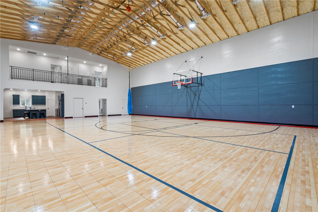 16556 East Hewitt Springs Road Springdale, AR 72764 - Photo 41 of 60 Spacious indoor court featuring hardwood flooring with court markings, a basketball hoop, and high ceilings with exposed wood trusses
