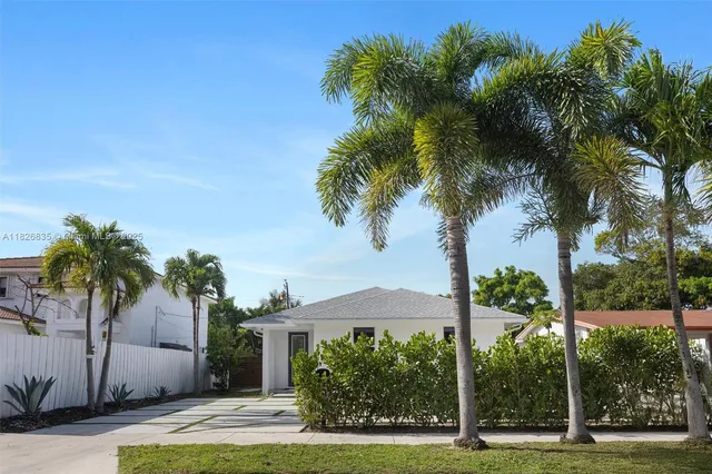 a palm tree sitting in front of a house with a big yard
