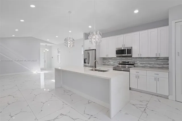 a kitchen with white cabinets appliances and a sink