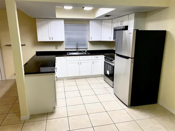 a kitchen with a refrigerator a stove top oven and cabinets