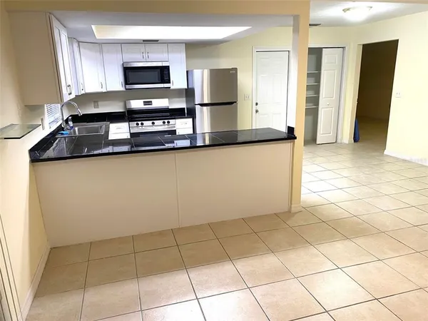 a kitchen with granite countertop a refrigerator and a stove top oven