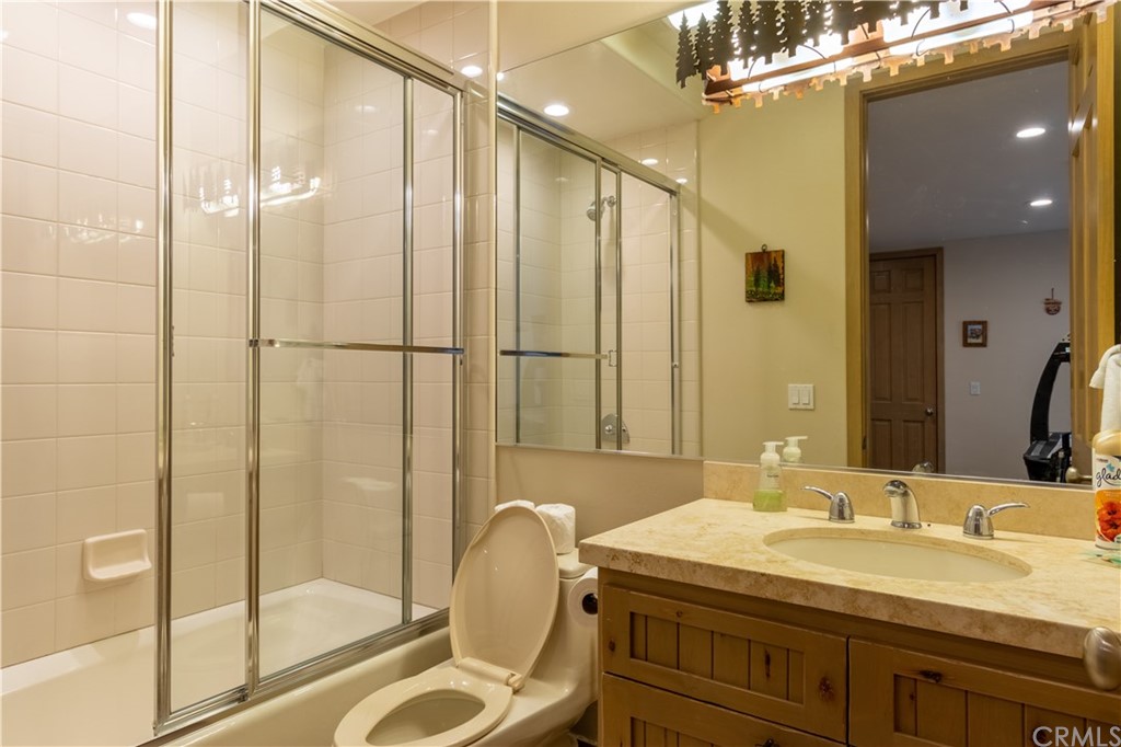 43490 Primrose Drive Big Bear Lake, CA 92315 - Photo 42 of 69 a bathroom with a granite countertop sink a mirror and a shower