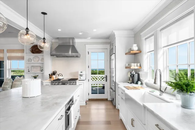 a large white kitchen with a large window and stainless steel appliances