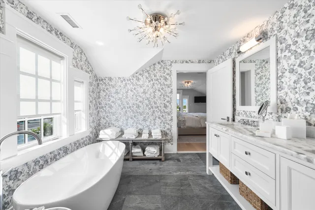 a spacious bathroom with a double vanity sink a large mirror a bathtub and a window