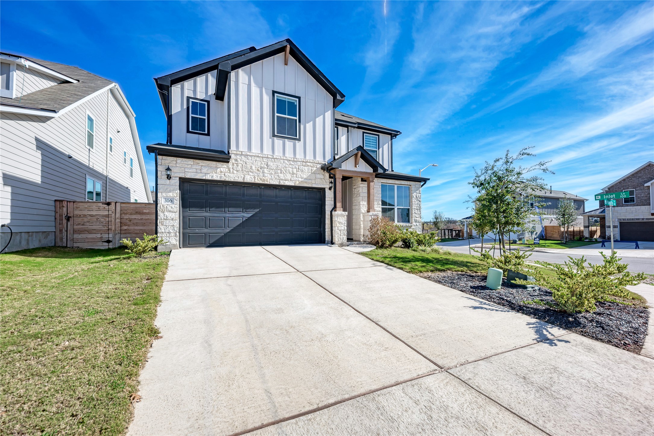 316 Regatta Trail Leander, TX 78641 - Photo 1 of 39 Contemporary two-story residence featuring a stone and vertical siding facade, an integrated two-car garage with a dark door, and a concrete driveway