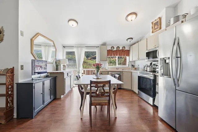 a kitchen with stainless steel appliances granite countertop a dining table chairs refrigerator and sink