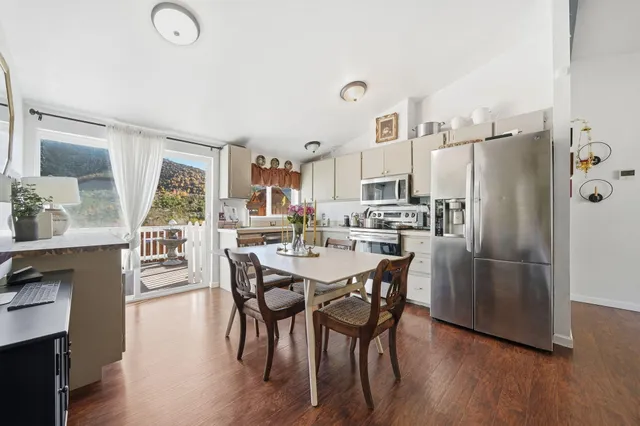a kitchen with stainless steel appliances a dining table chairs and wooden floor
