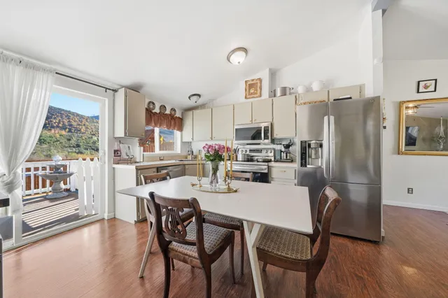 a dining room with stainless steel appliances a dining table and chairs