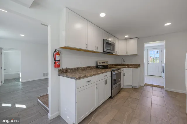 a kitchen with stainless steel appliances granite countertop a stove a sink and a refrigerator