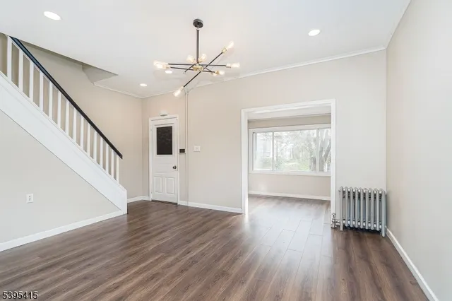 a view of an empty room with wooden floor windows and a chandelier