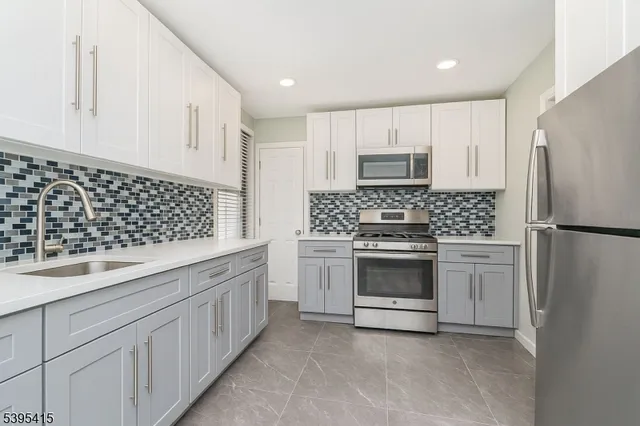 a kitchen with white cabinets and stainless steel appliances