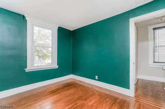 a view of empty room with window and wooden floor