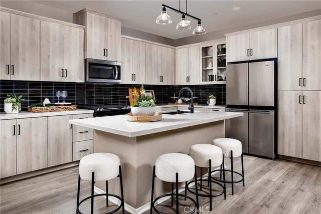 a kitchen with stainless steel appliances a white table chairs refrigerator and sink