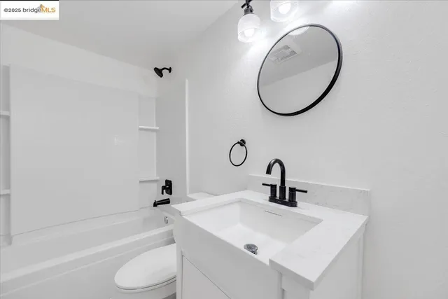 a bathroom with a toilet sink vanity and mirror