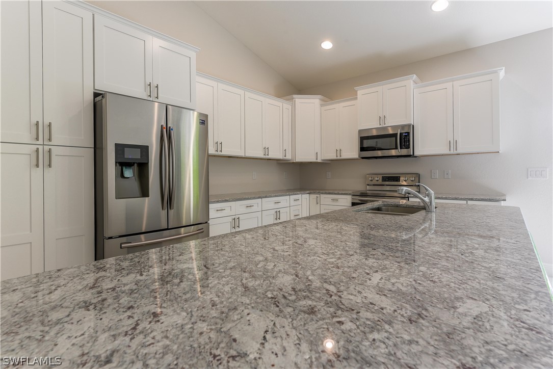 8160 Anhinga Road Fort Myers, FL 33967 - Photo 3 of 25 a kitchen with stainless steel appliances granite countertop a refrigerator a stove a sink and white cabinets