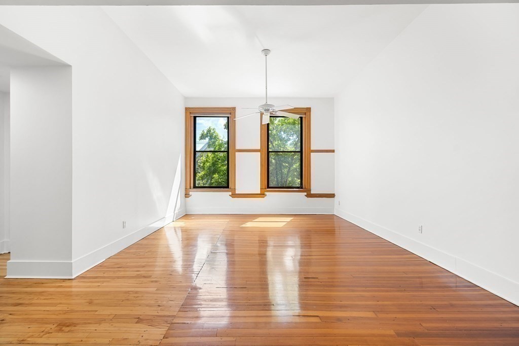 a view of an empty room with window and wooden floor