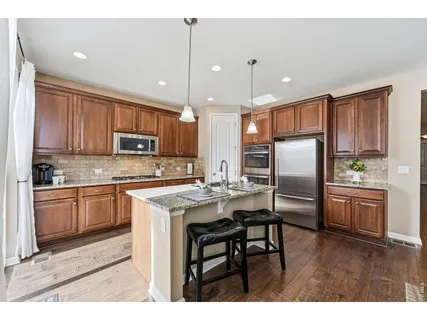 a kitchen with kitchen island granite countertop wooden cabinets and refrigerator