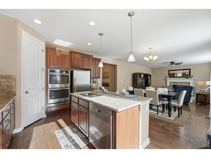 a kitchen with stainless steel appliances kitchen island granite countertop a sink refrigerator and cabinets