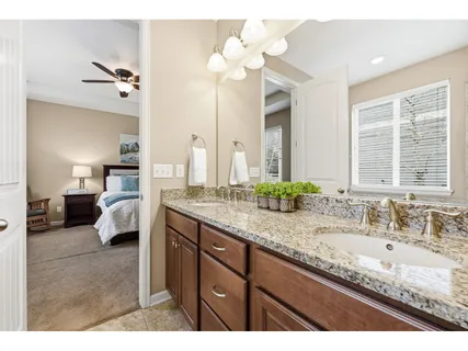a en suite bathroom with a granite countertop sink and a mirror