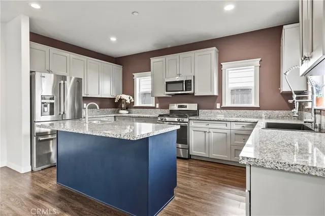 a kitchen with kitchen island granite countertop a sink stove and refrigerator