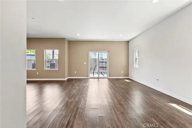 a view of an empty room with wooden floor and windows