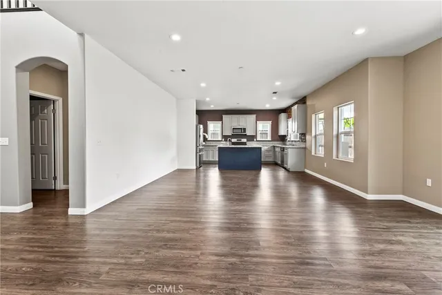 a kitchen with stainless steel appliances granite countertop a stove a sink dishwasher a refrigerator and white cabinets with wooden floor