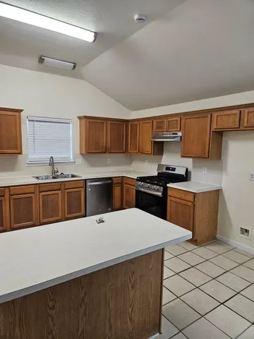 a kitchen with stainless steel appliances a sink a stove top oven a counter space and cabinets