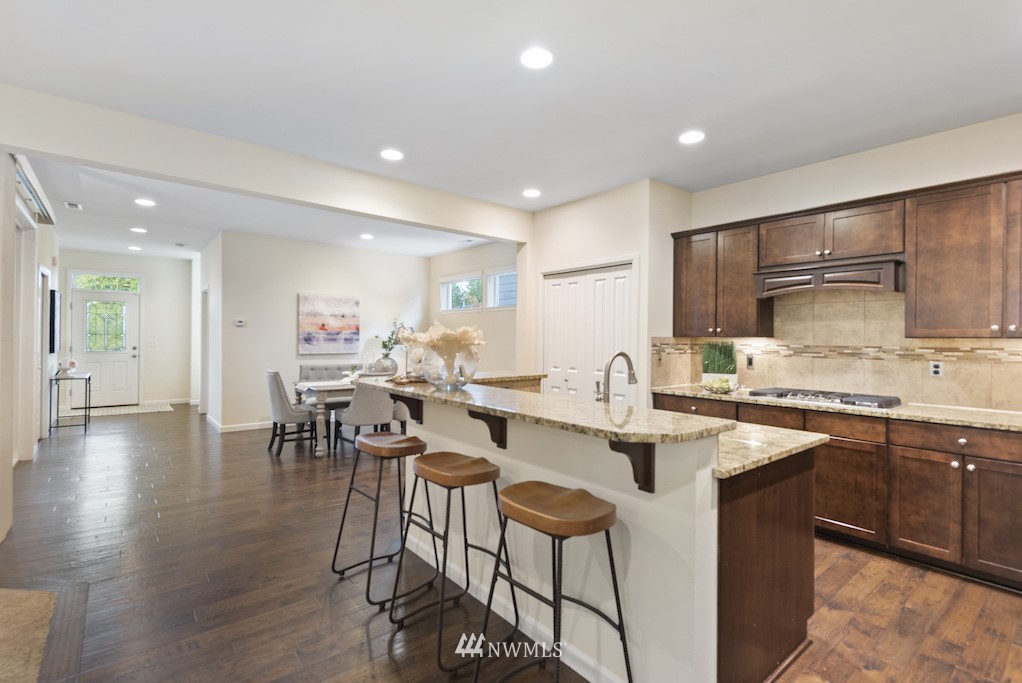 16232 Southeast 139th Court Renton, WA 98059 - Photo 7 of 23 a kitchen with stainless steel appliances granite countertop a stove top oven a sink a refrigerator and white cabinets with wooden floor