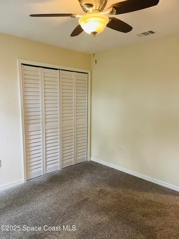 an empty room with a ceiling fan and a window