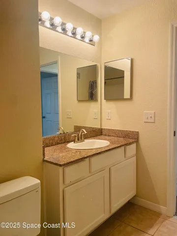 a bathroom with a granite countertop sink a toilet and mirror