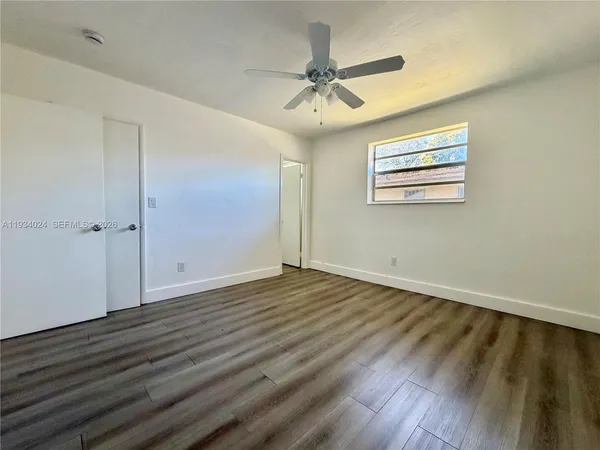 an empty room with wooden floor chandelier fan and windows