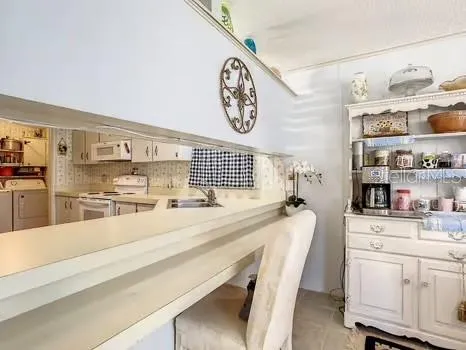 a kitchen with granite countertop a sink a stove a refrigerator and white cabinets