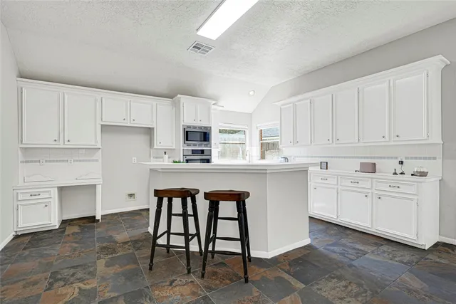 a kitchen with stainless steel appliances granite countertop a stove a sink dishwasher and a refrigerator with white cabinets
