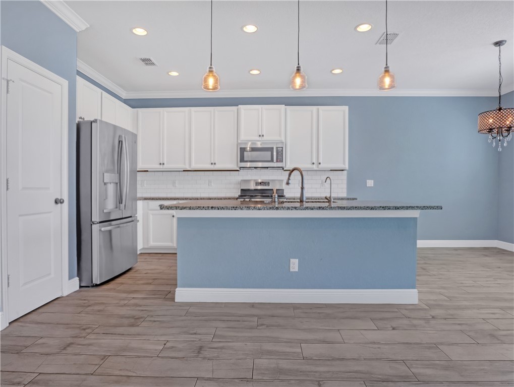 1756 Willows Square Vero Beach, FL 32966 - Photo 11 of 35 a kitchen with stainless steel appliances granite countertop a stove a refrigerator a sink and white cabinets with wooden floor