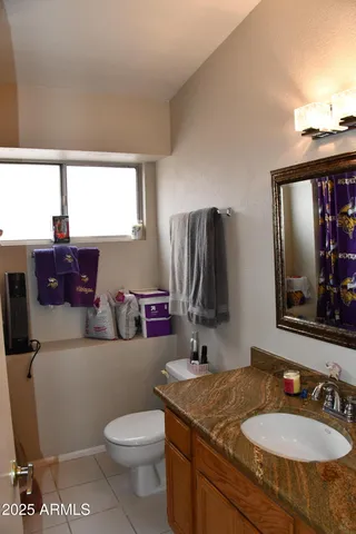 a bathroom with a granite countertop toilet sink and mirror
