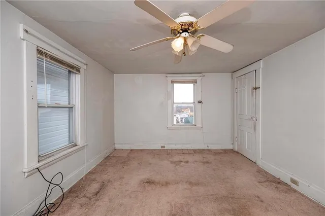 an empty room with windows and fan