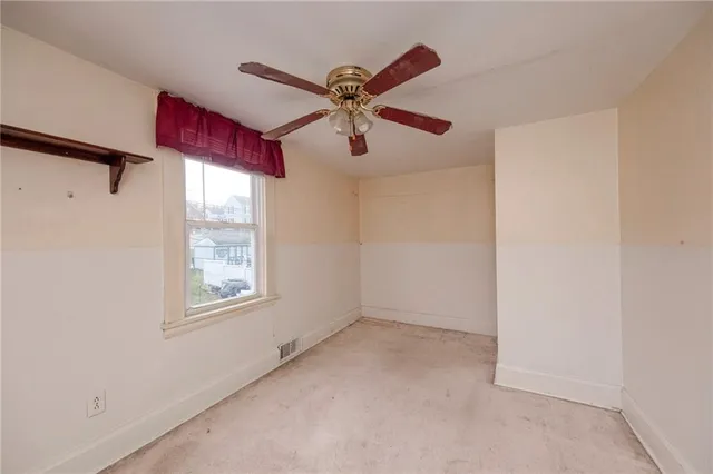 a view of empty room with window and ceiling fan