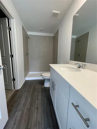 a bathroom with a sink a toilet a mirror and shower