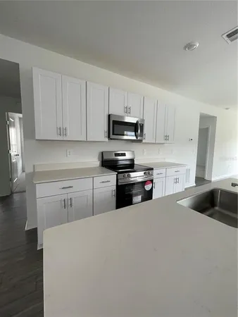a kitchen with granite countertop white cabinets and stainless steel appliances