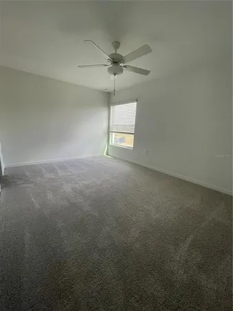 an empty room with a window and a fan