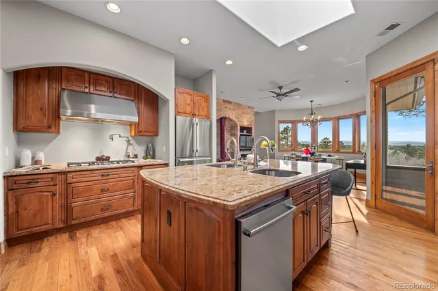 a kitchen with stainless steel appliances granite countertop a sink a stove and a wooden cabinets