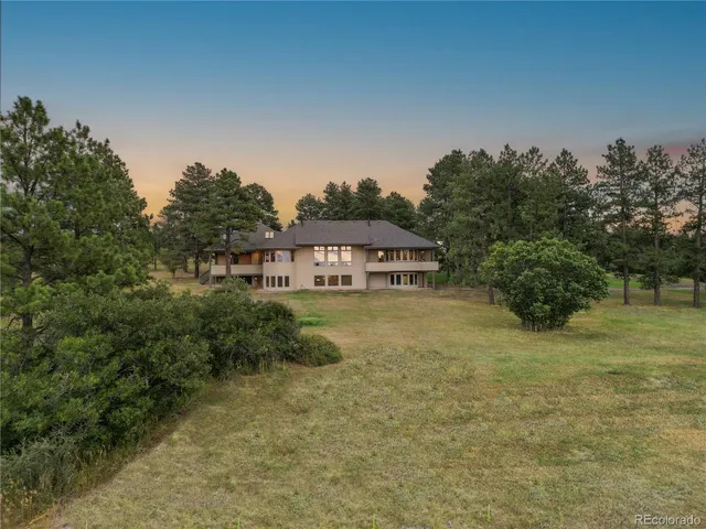 a view of a big house with a big yard and large trees
