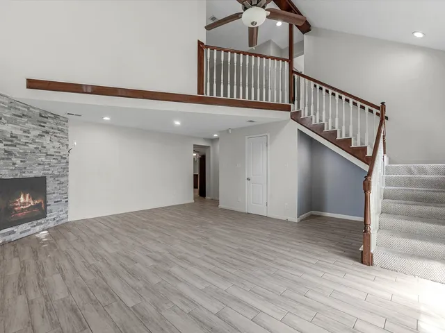 a view of an empty room with wooden floor stairs and a fireplace
